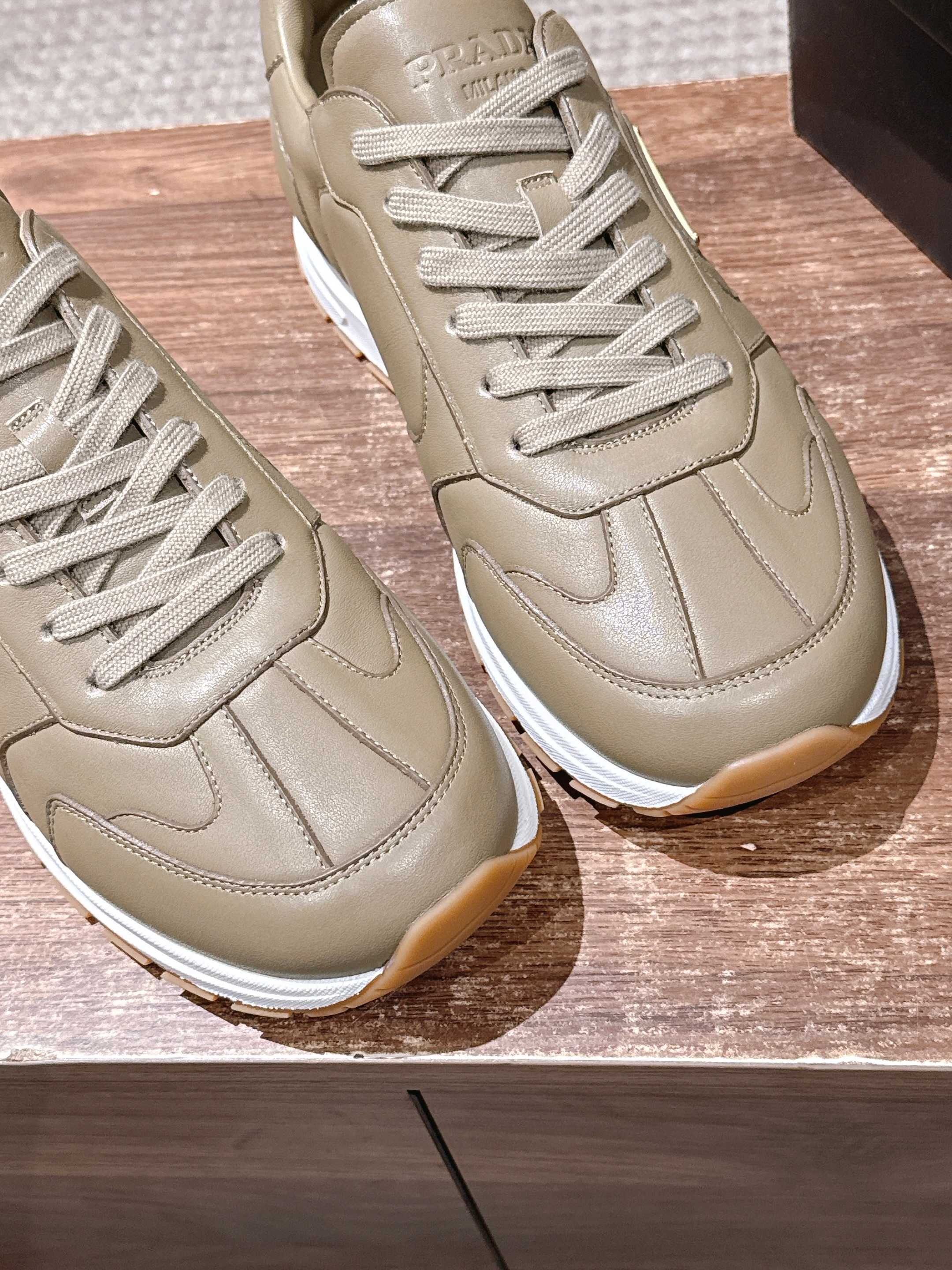 Prada unisex light beige sneakers, close-up of laces and leather panels.