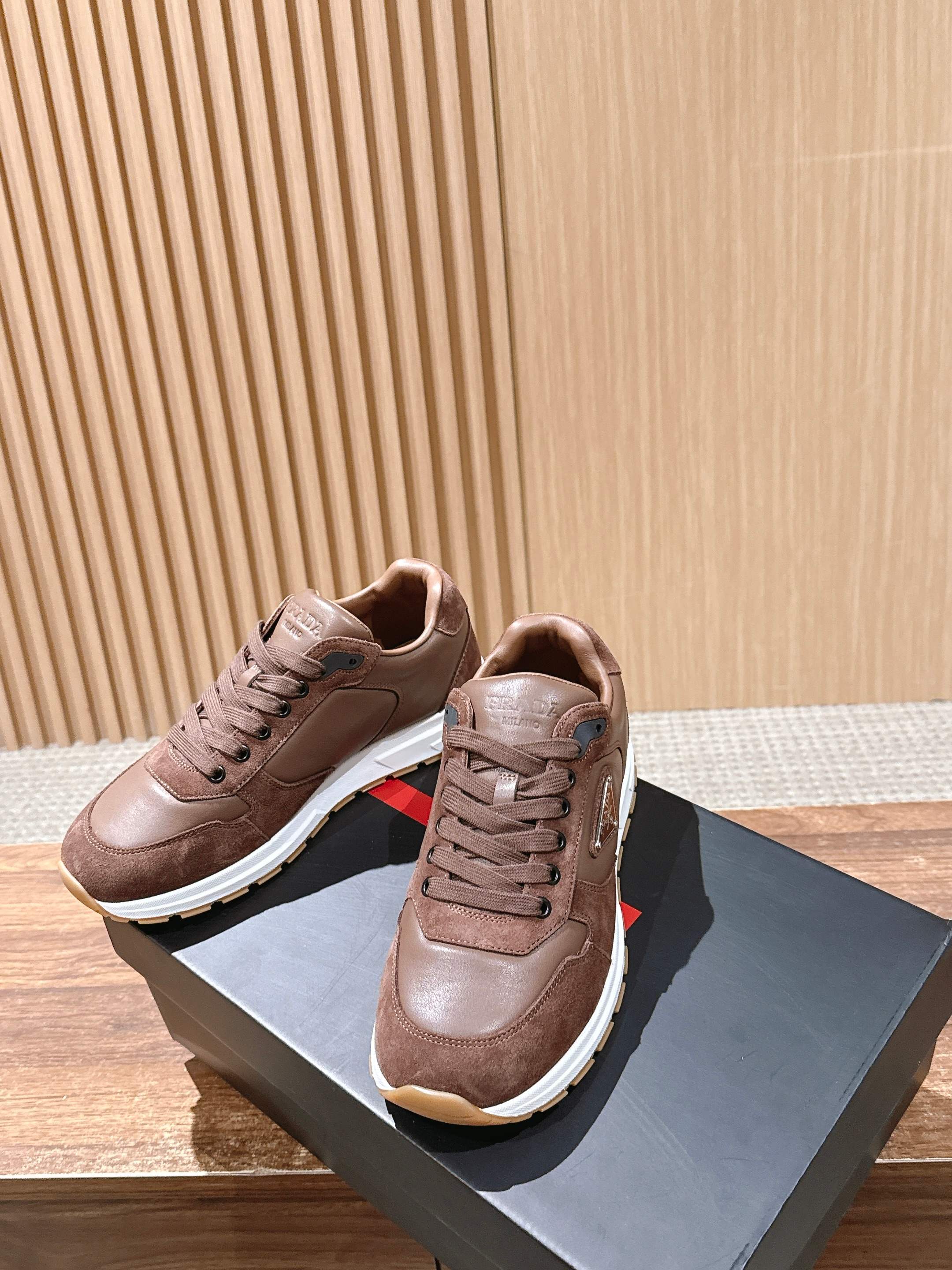 Taupe leather unisex sneakers with lace-up uppers and white rubber soles.