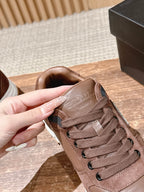 Taupe lace-up sneaker close-up with small logo detail on the tongue.