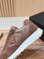 Taupe leather sneaker with lace-up, logo badge, and white sole.