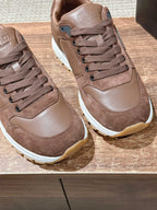 Taupe lace-up sneakers with textured panels, contrasting white sole, and laces.