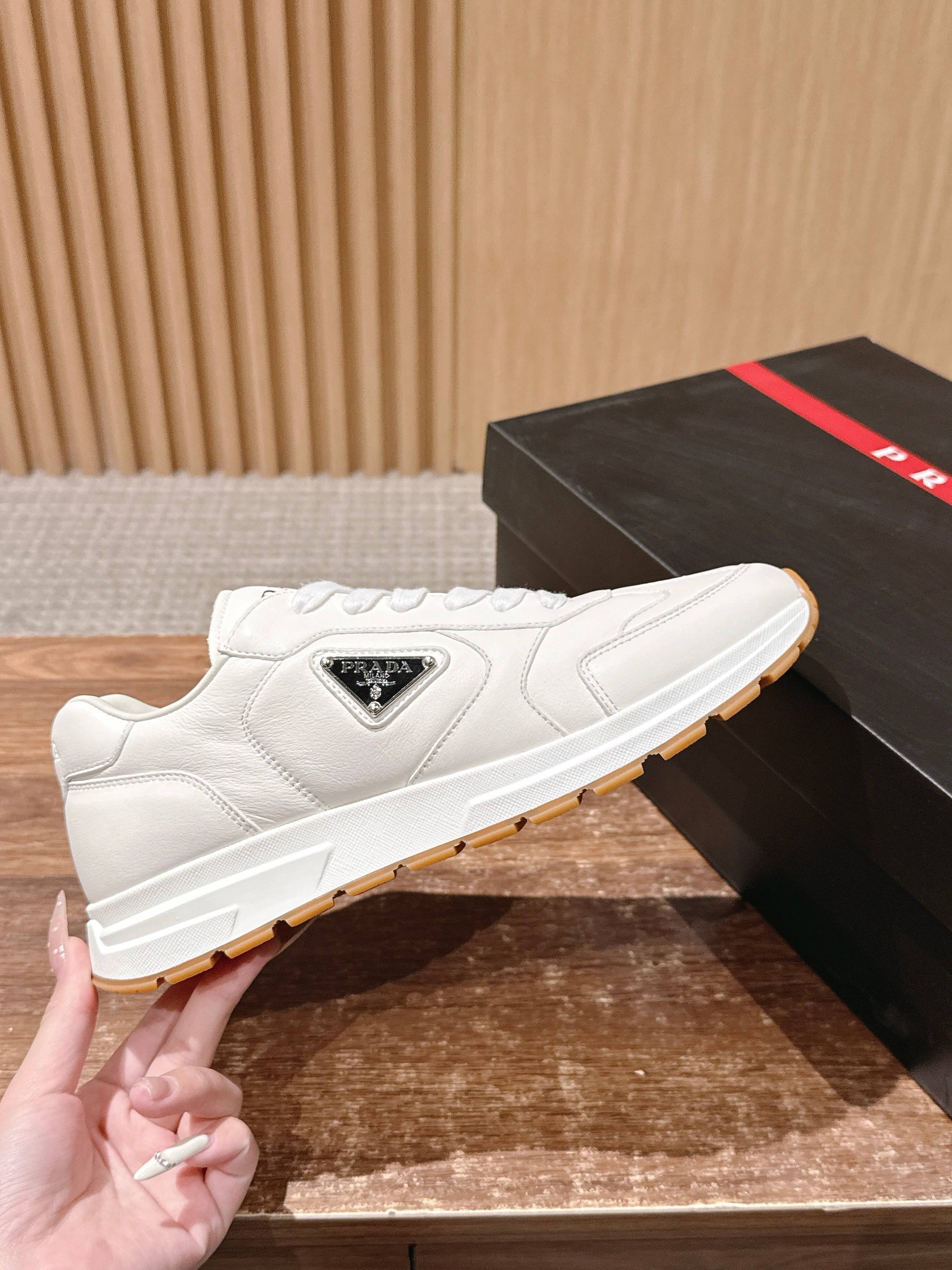 Prada white leather low-top sneakers with triangular logo patch and tan sole