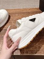 Prada white leather sneaker with triangular logo patch and tan rubber sole