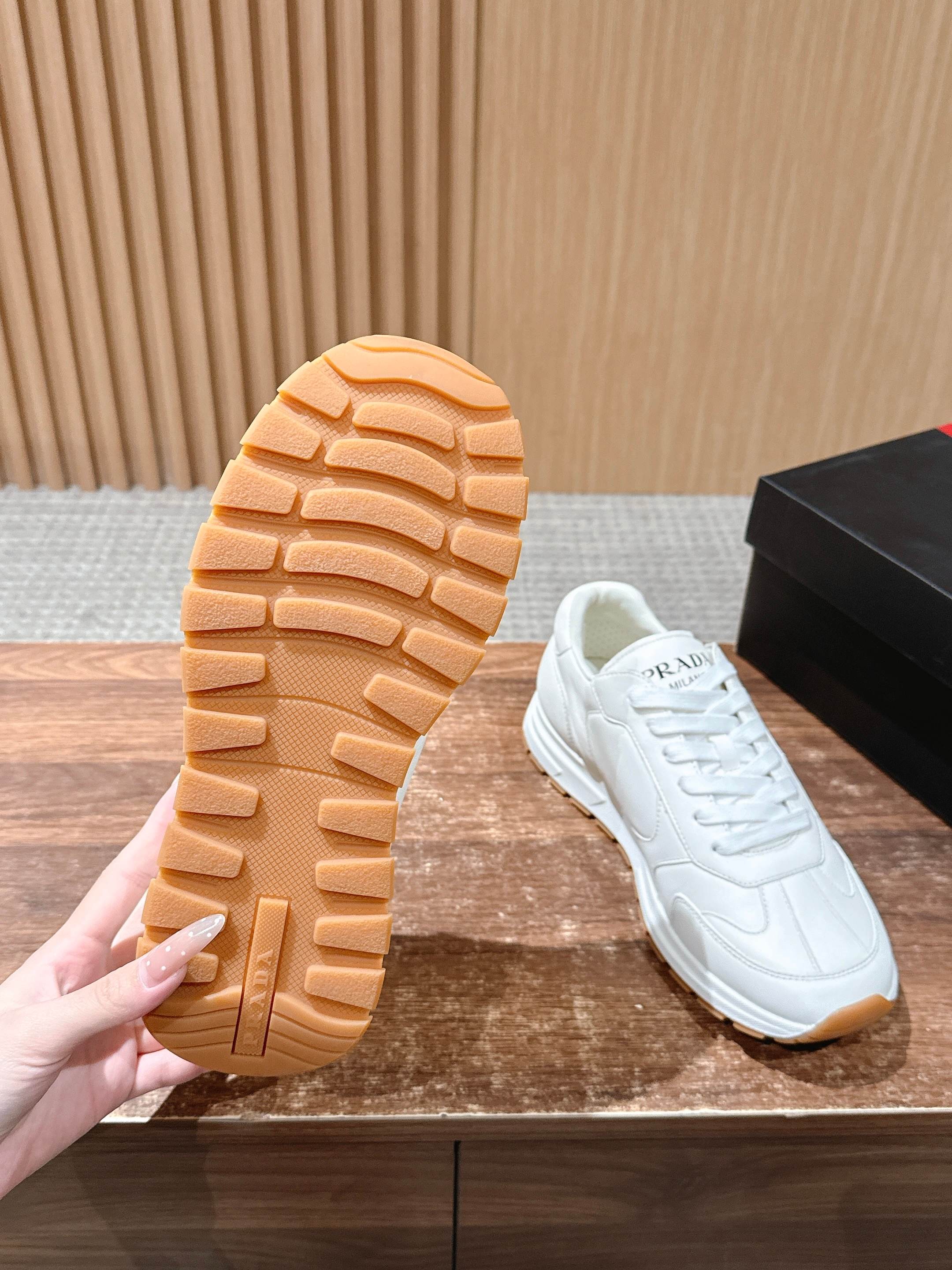 Prada white sneaker outsole view with tan rubber tread pattern