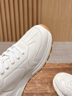 Prada white leather sneaker side view with lace eyelets and tan rubber outsole