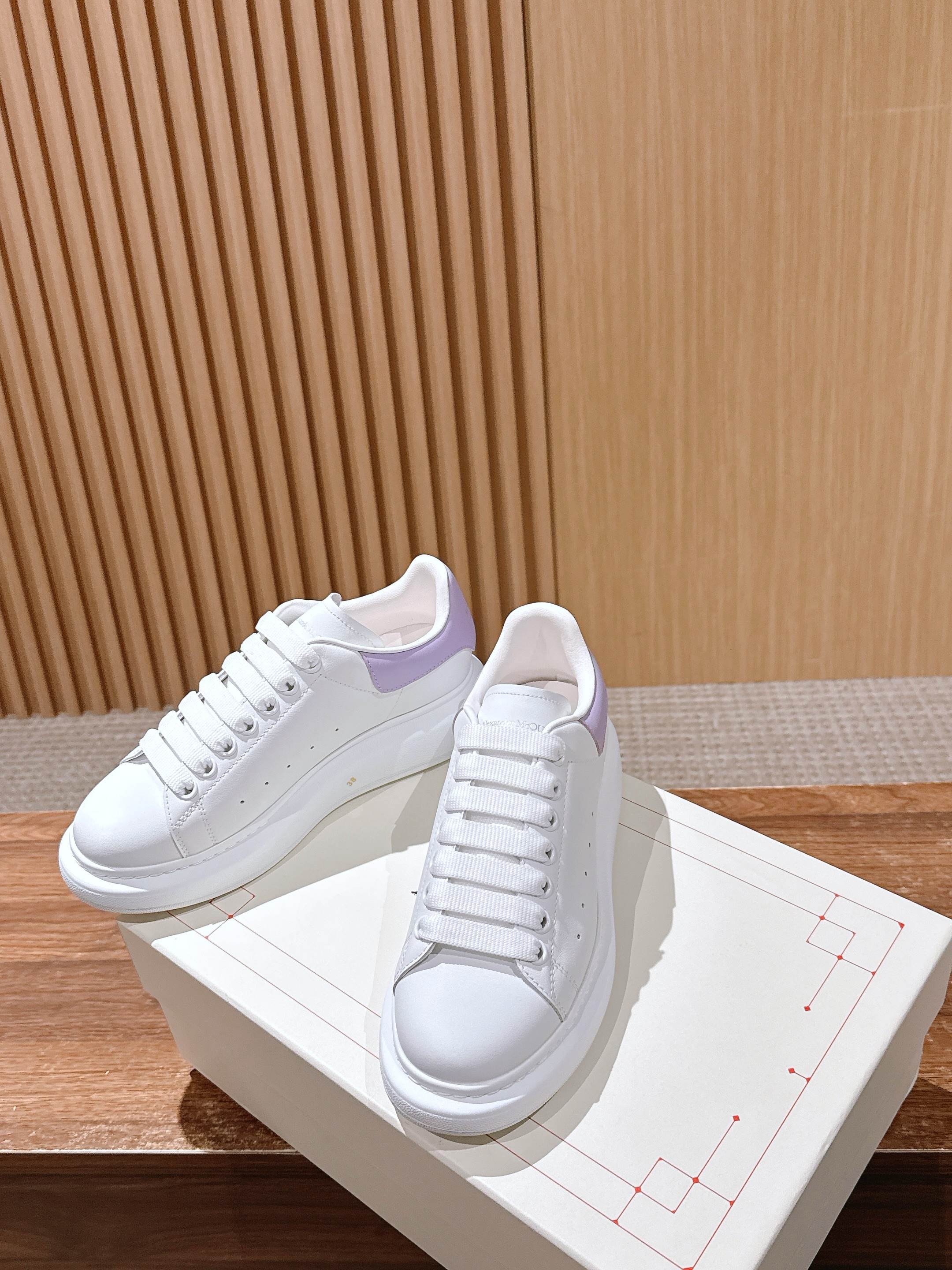 White leather sneakers with lavender trim, front and side angles on box
