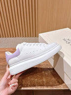 White leather sneakers with lavender heel panel and perforated toe, held up