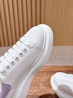 Close-up white leather sneaker with lavender side panel and lace detail