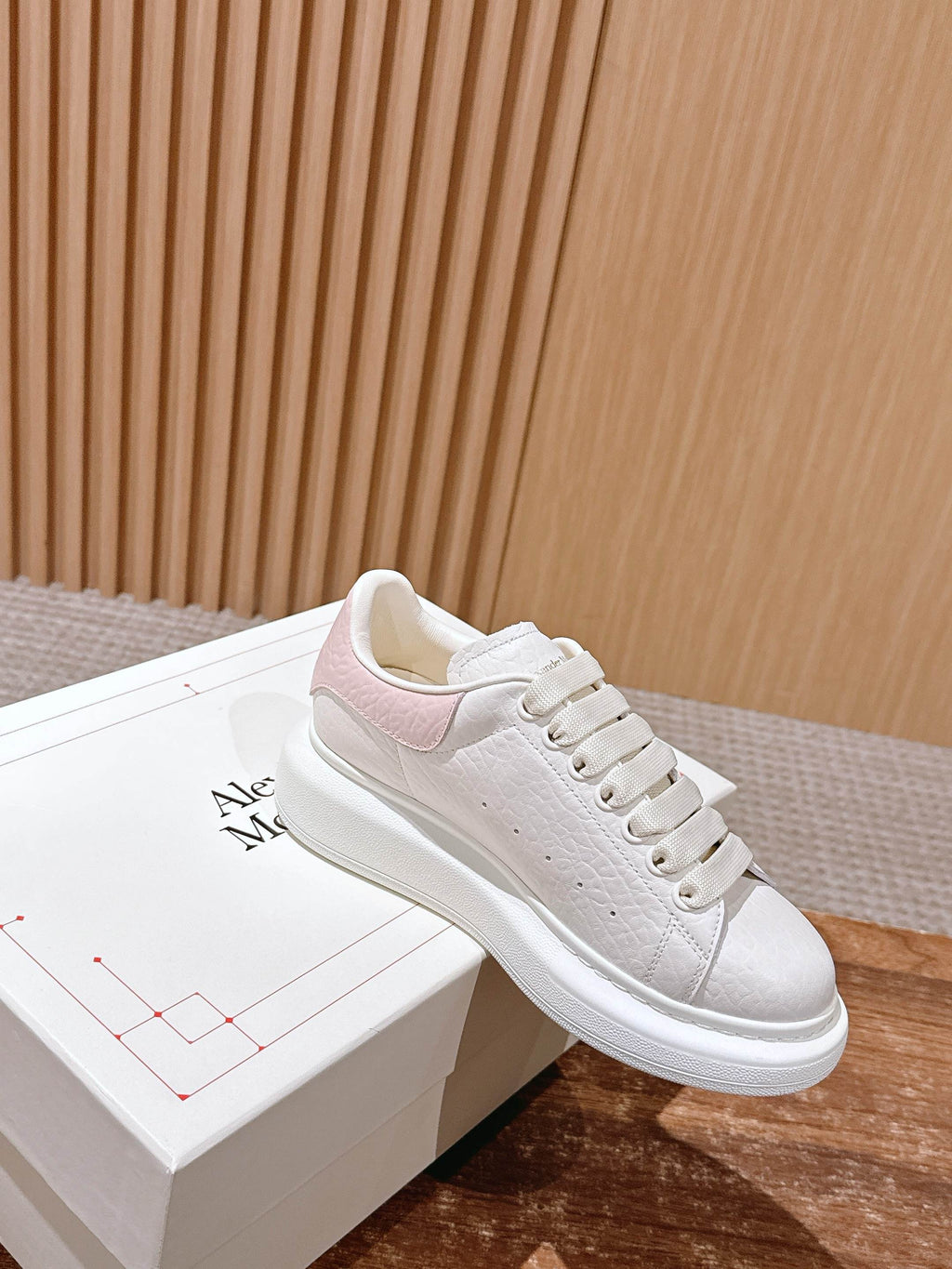 White leather sneakers with pink side panel accent and lace-up closure