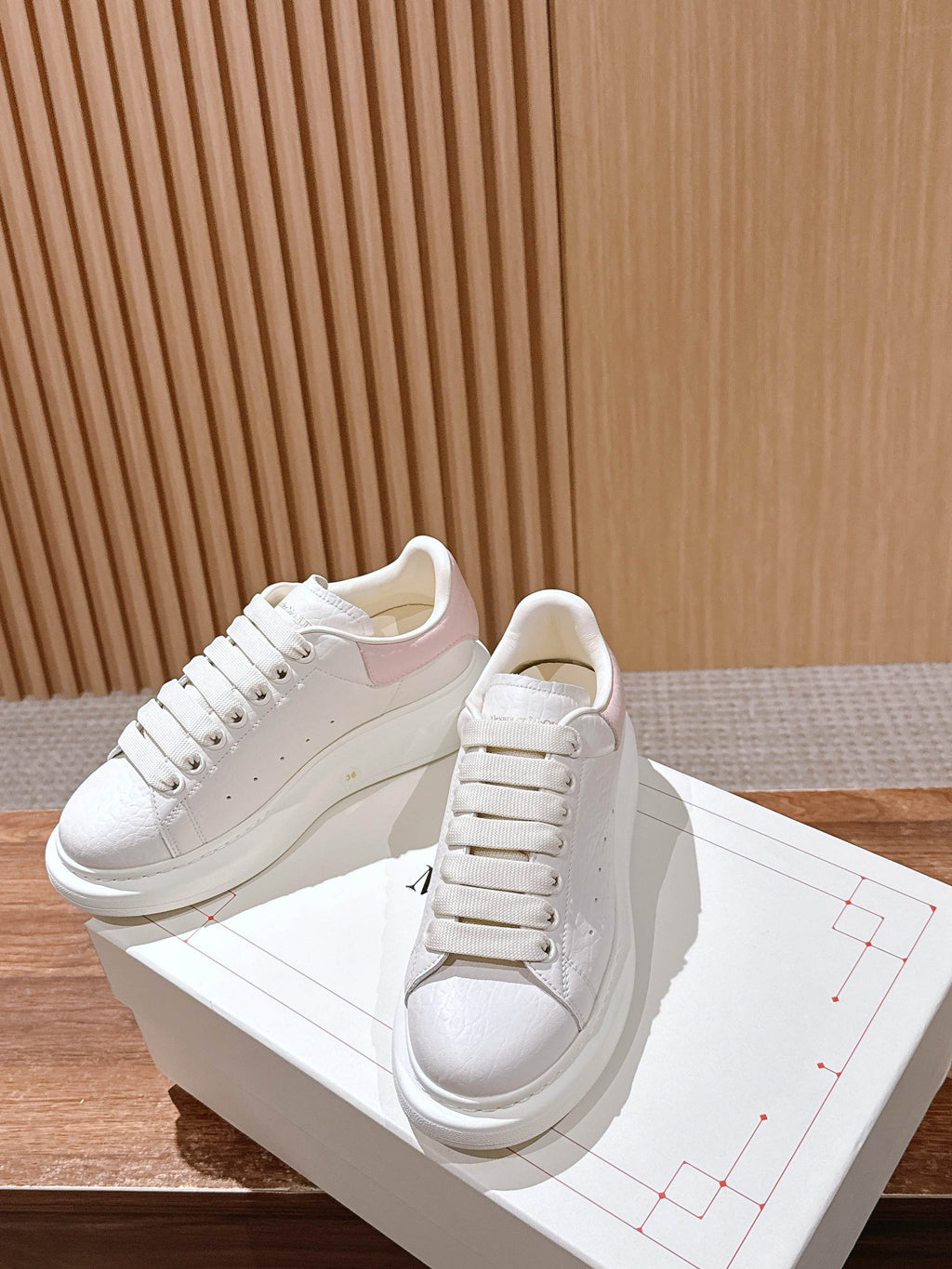 White leather lace-up sneakers with subtle texture and thick white rubber sole