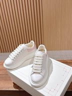 White leather lace-up sneakers with subtle texture and thick white rubber sole