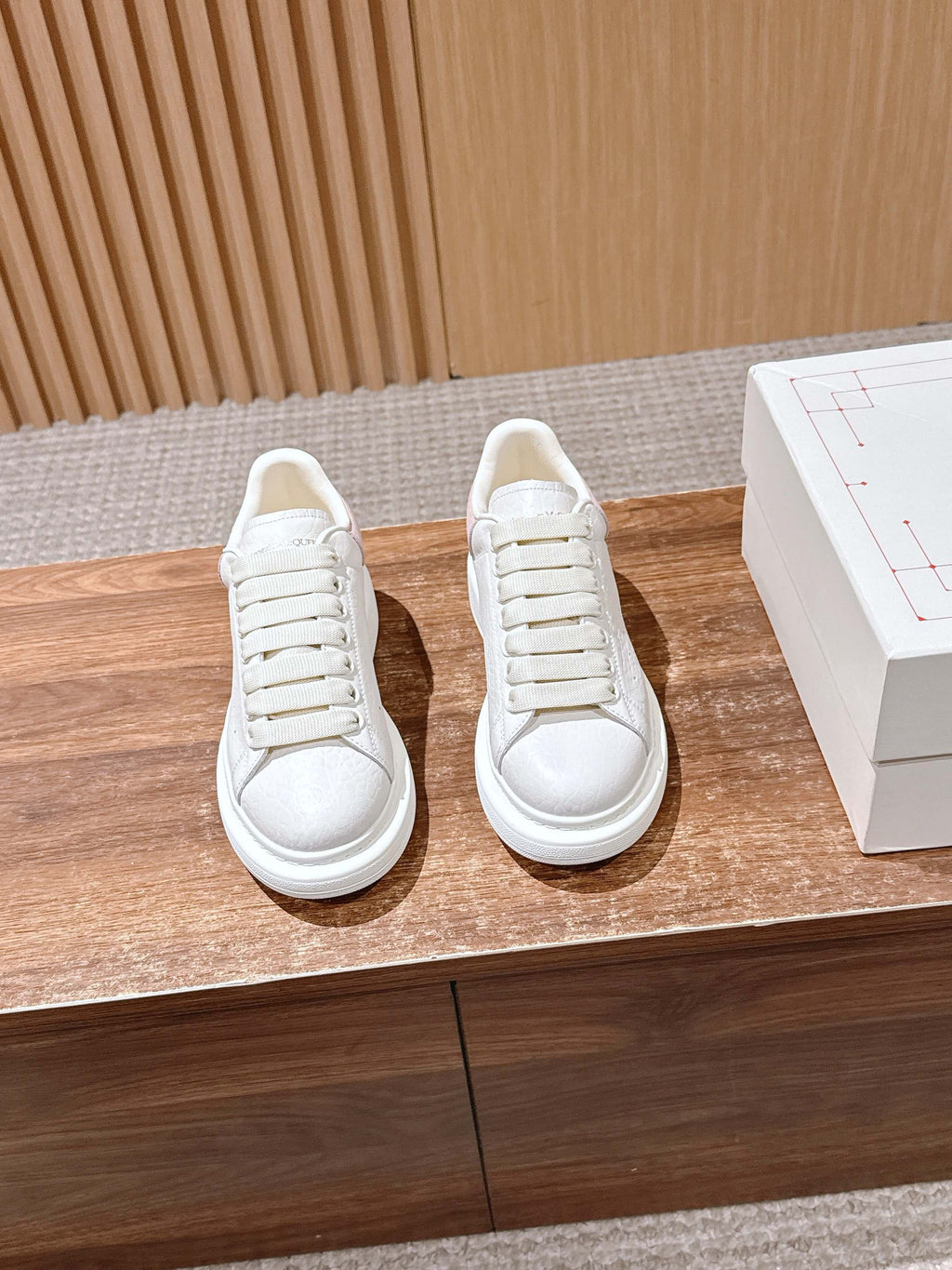 Pair of white leather lace-up sneakers with textured toe and rubber sole