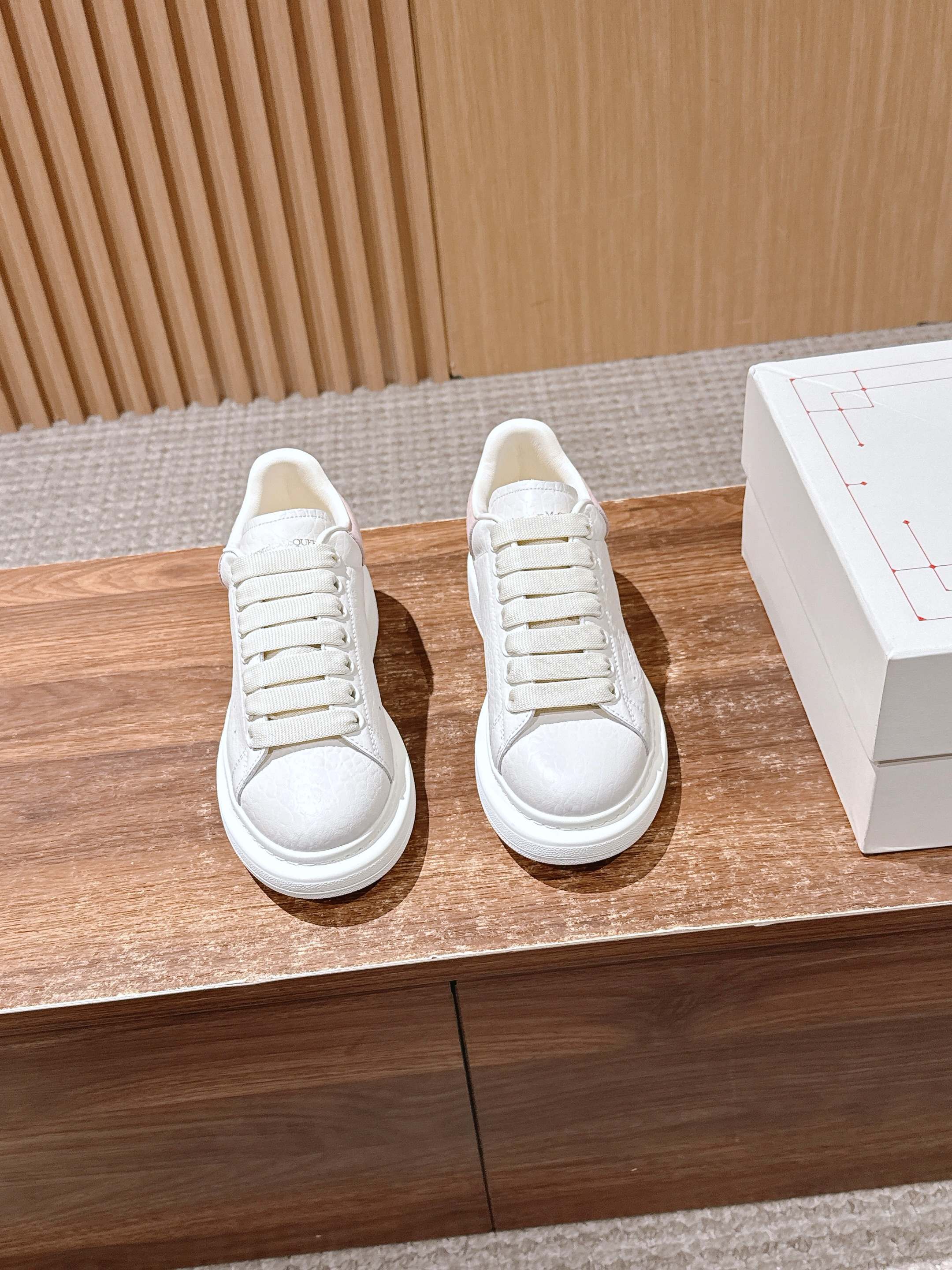 Pair of white leather lace-up sneakers with textured toe and rubber sole