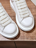Close-up of white leather sneakers showing lace row stitching and rounded toe