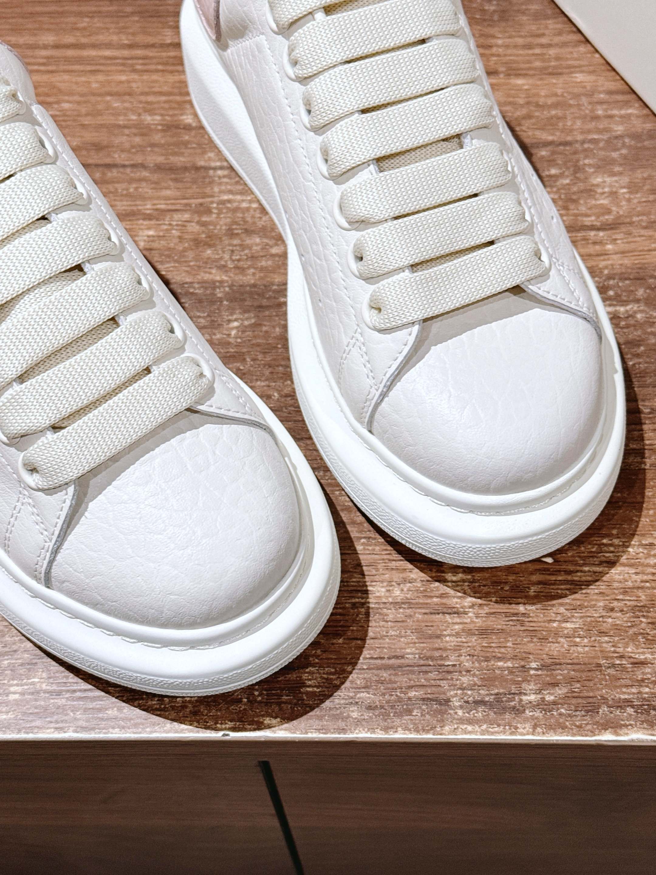Close-up of white leather sneakers showing lace row stitching and rounded toe