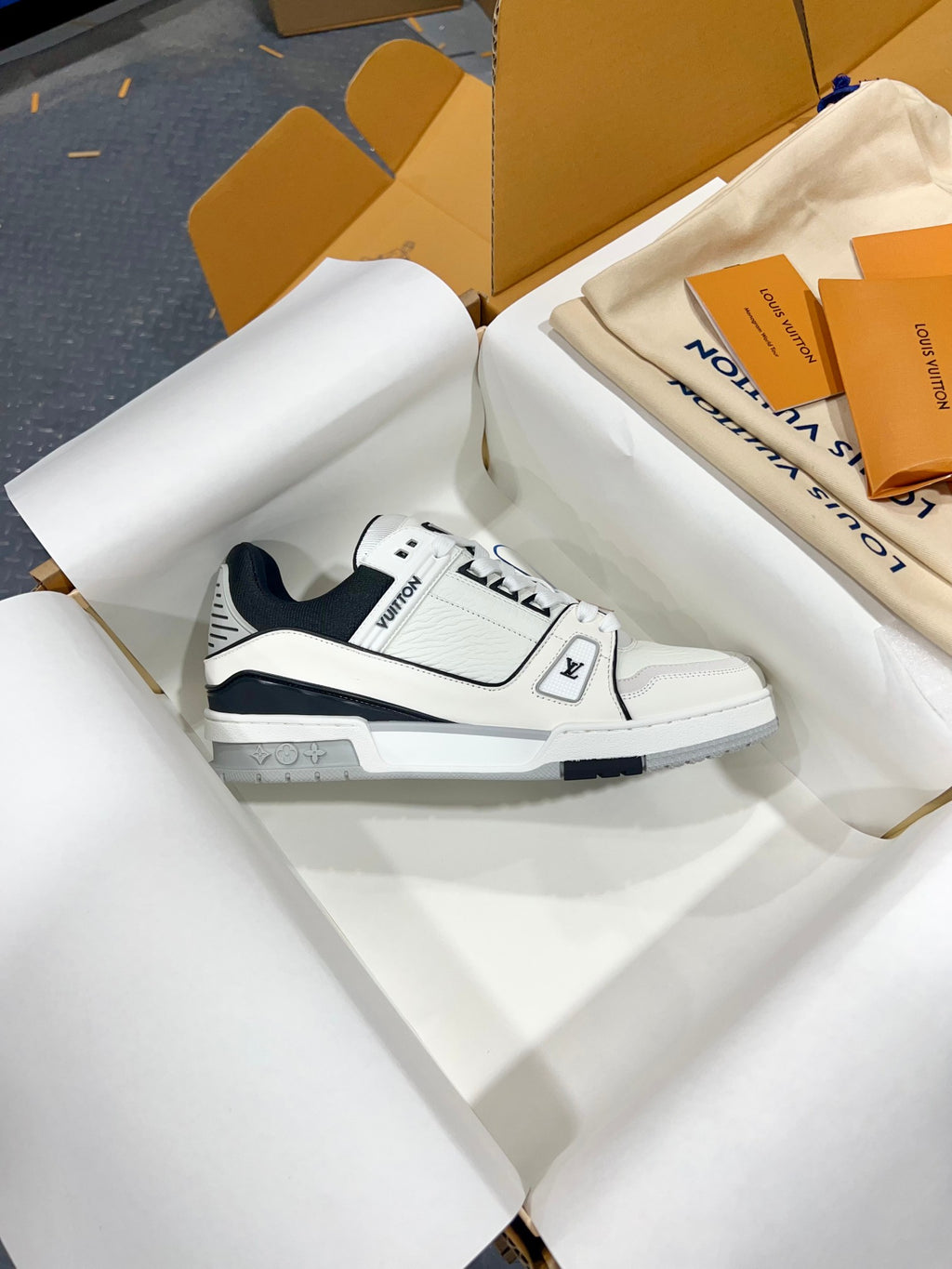 White Louis Vuitton low-top trainer shoe with navy collar and blue emblem