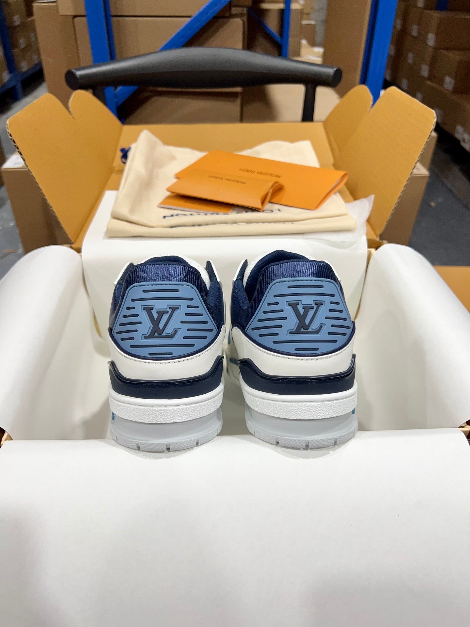 Louis Vuitton trainer sneakers, rear view with navy circular logo on heel and white soles.
