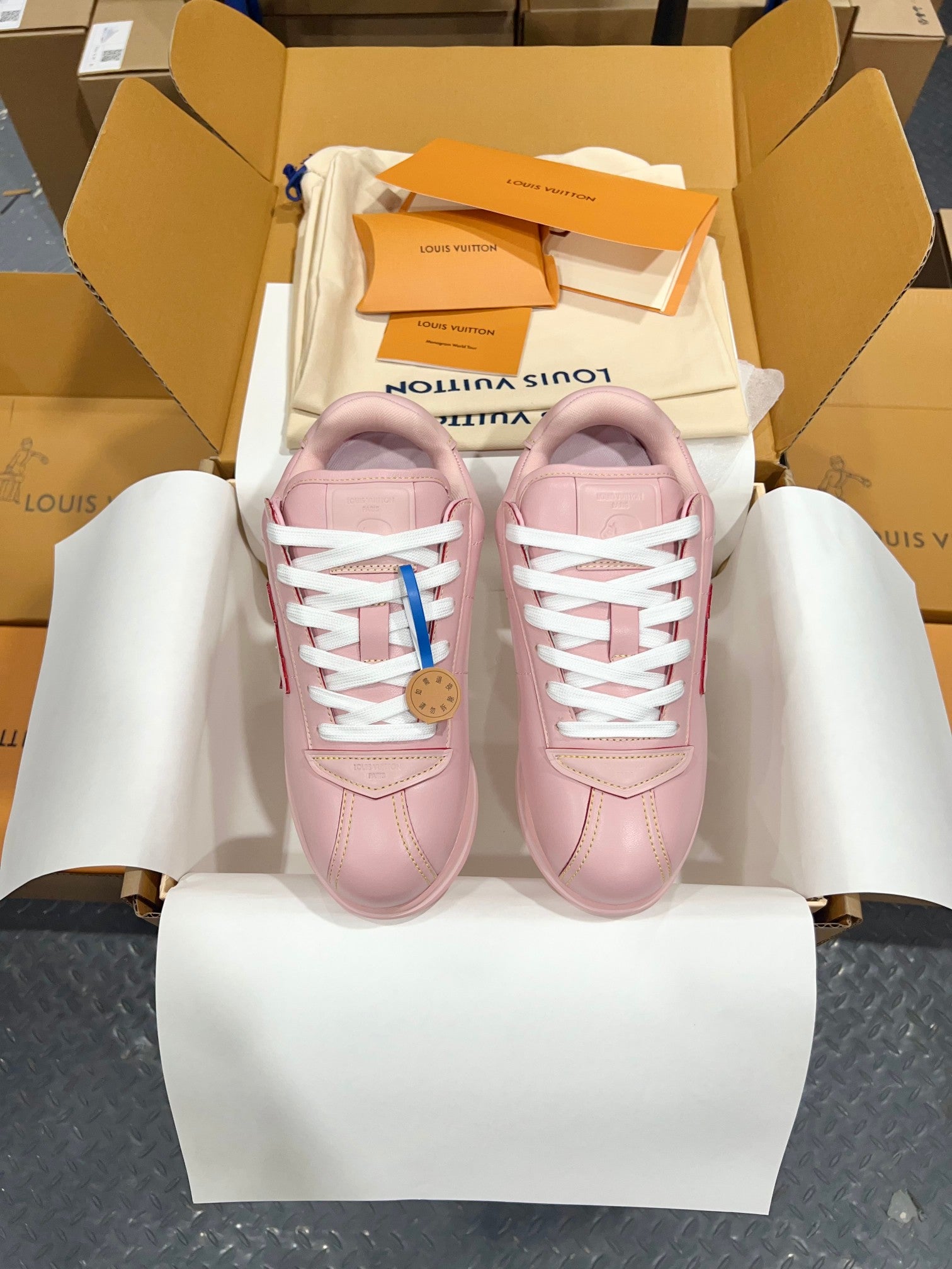 Louis Vuitton pink low-top sneakers with white laces, shown as a pair in open shoebox.