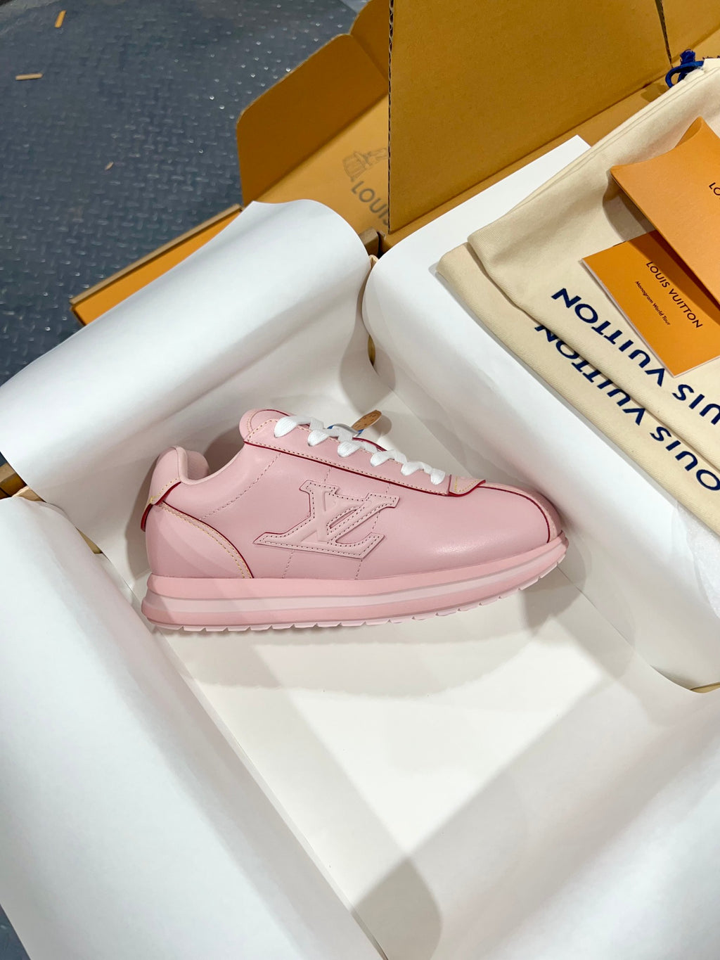 Louis Vuitton pink low-top sneaker with white laces, one shoe displayed on tissue in box.
