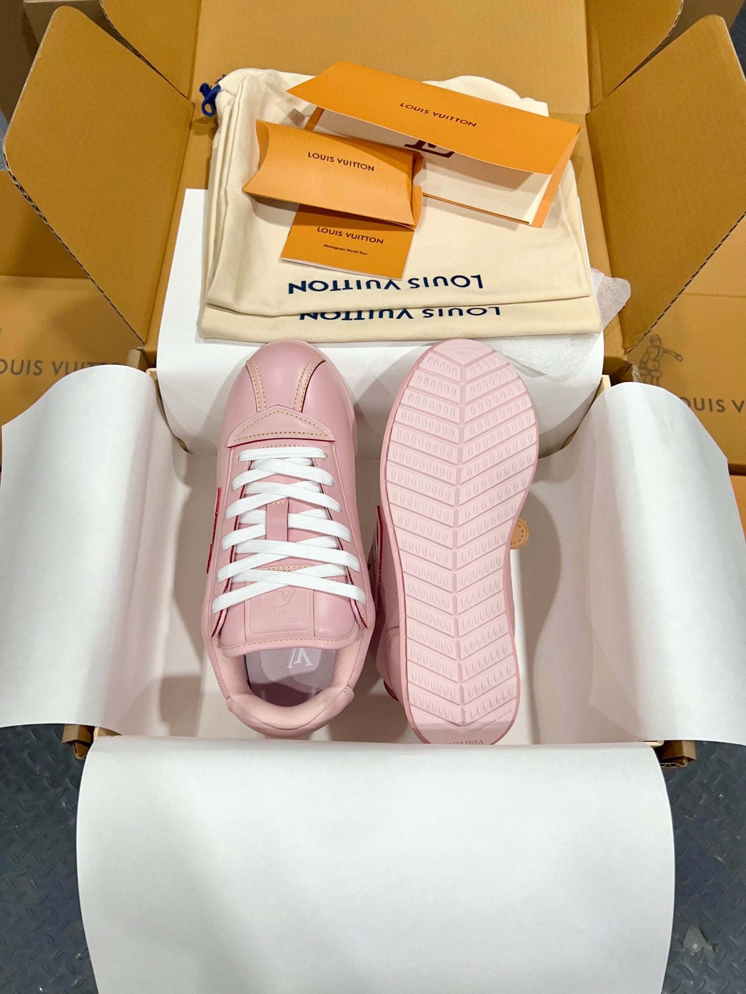 Louis Vuitton pink low-top sneakers with white laces, outsole view in open shoebox.