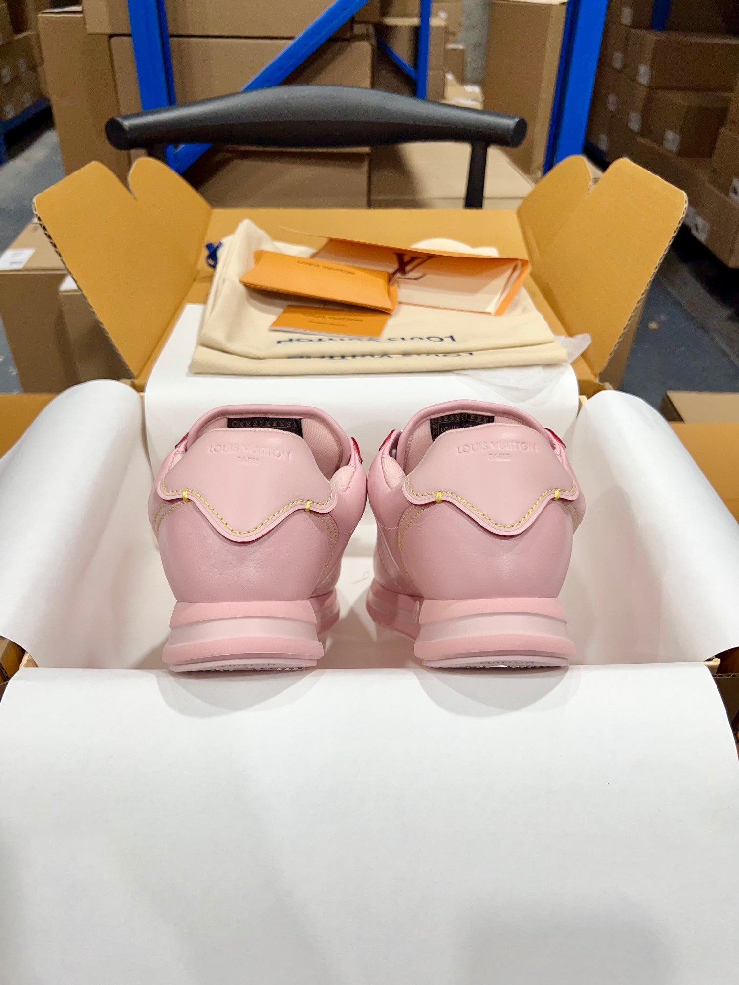 Louis Vuitton pink low-top sneakers with white laces, back view with heels facing camera in box.