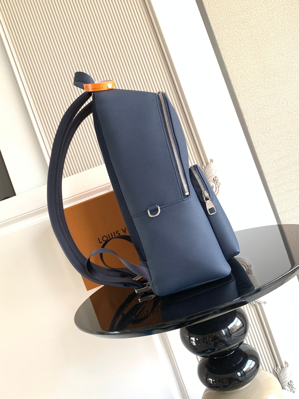 Navy leather backpack with zipper pocket, top handle, and adjustable strap