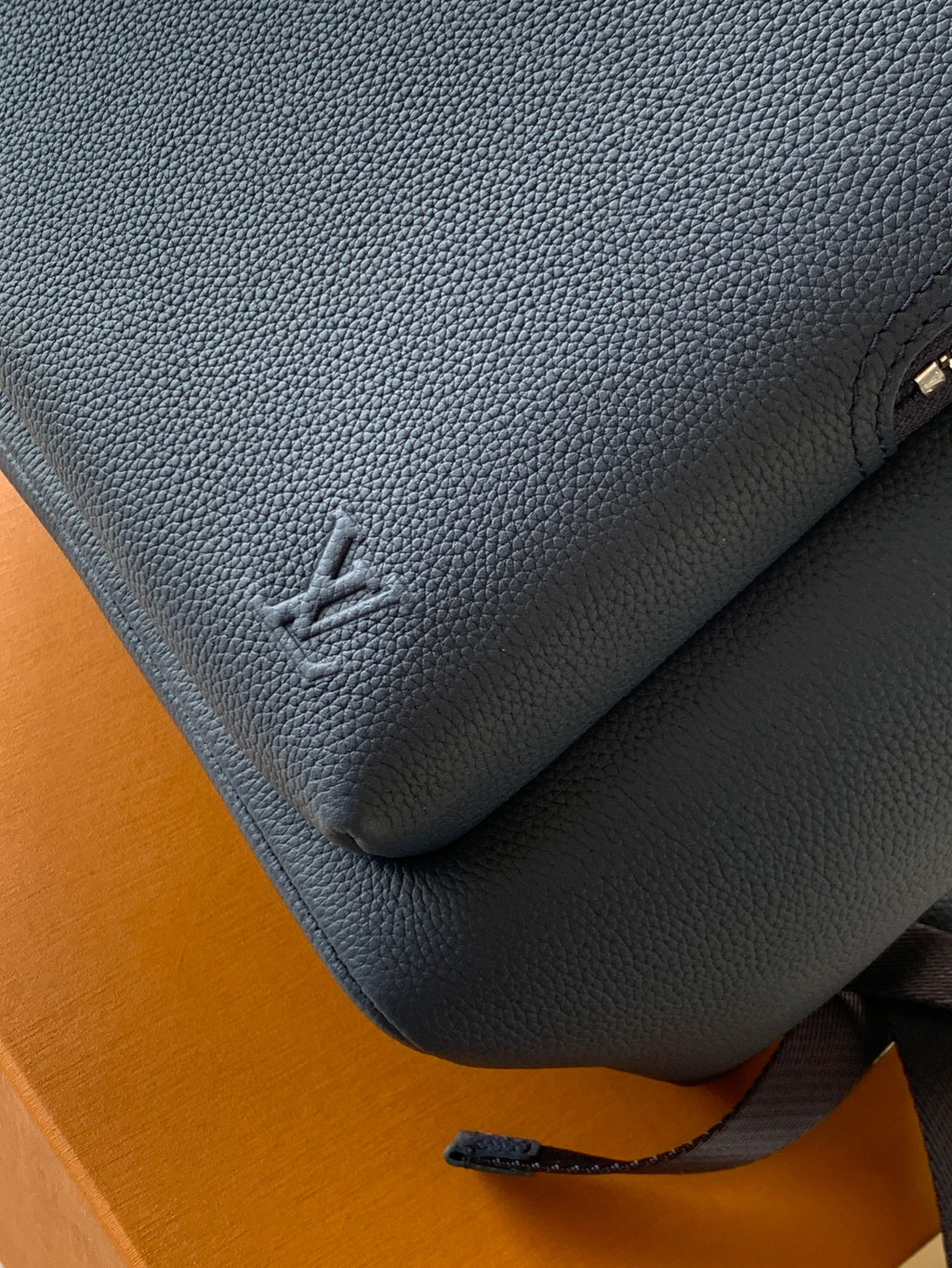 Navy leather backpack with embossed monogram and stitched corner detail