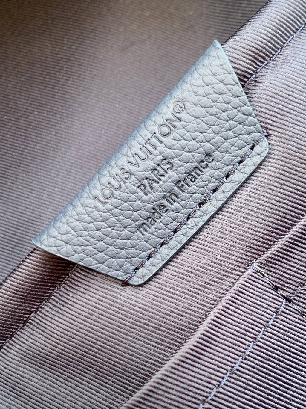 Louis Vuitton mini backpack leather label with embossed text and stitch edges