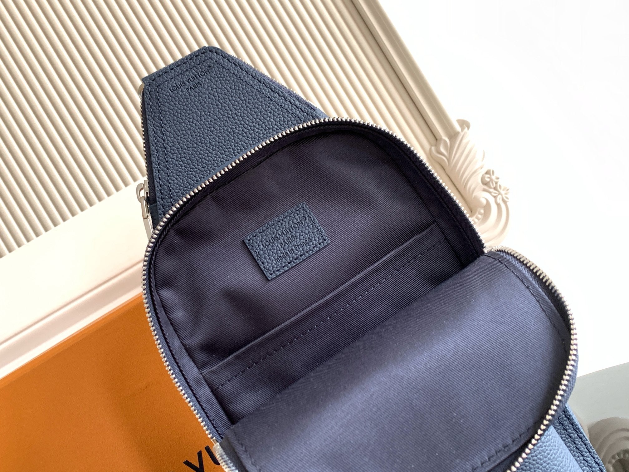 Small crossbody bag interior, dark fabric lining and zipper opening with patch
