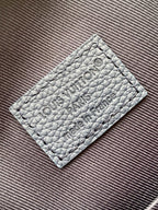 Louis Vuitton logo leather patch on blue bag with embossed text