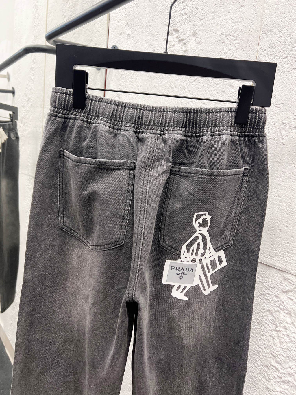 Gray denim pants with front patch pocket and white graphic emblem