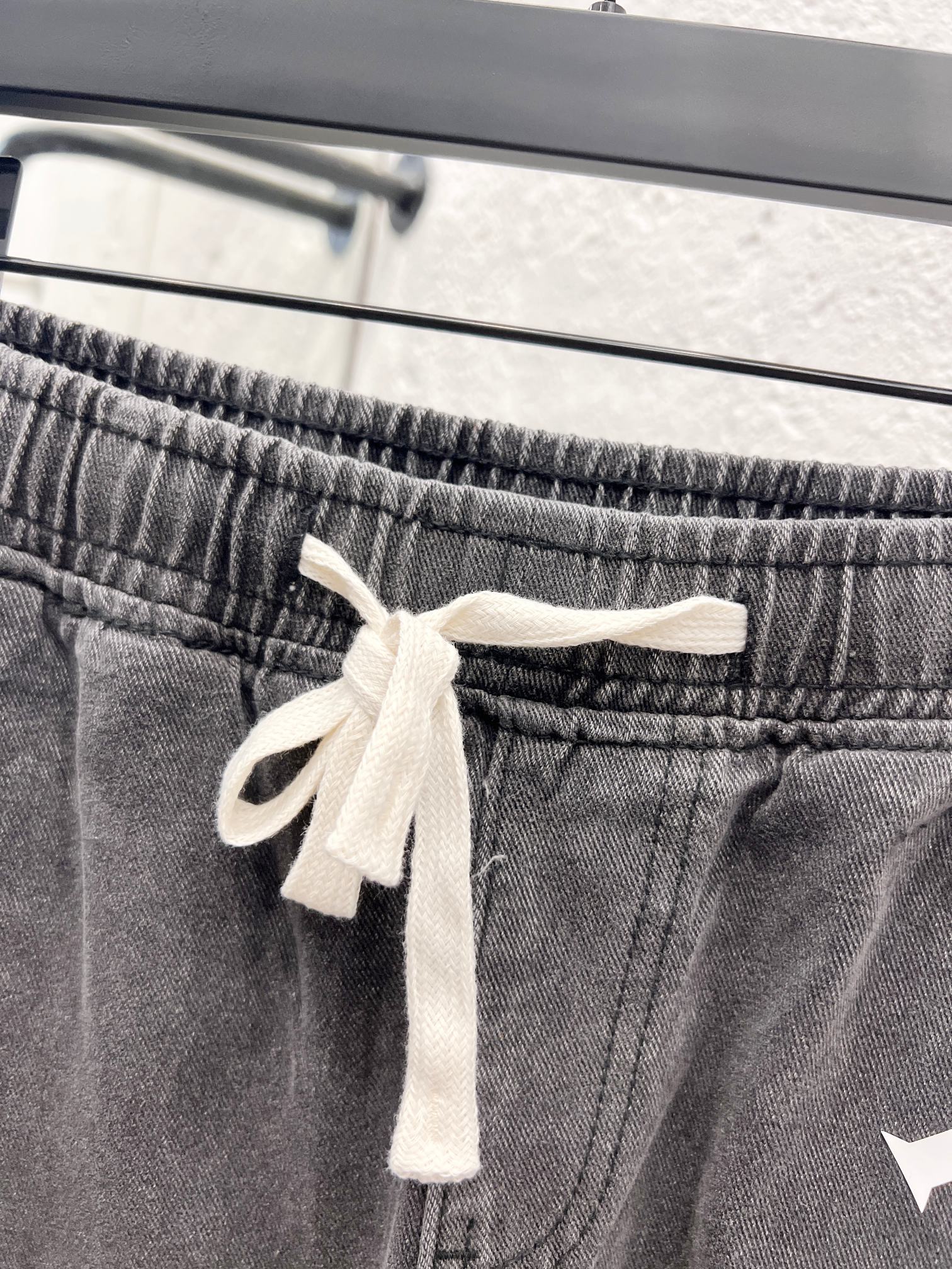 Gray denim pants waistband with white drawstring and stitched elastic