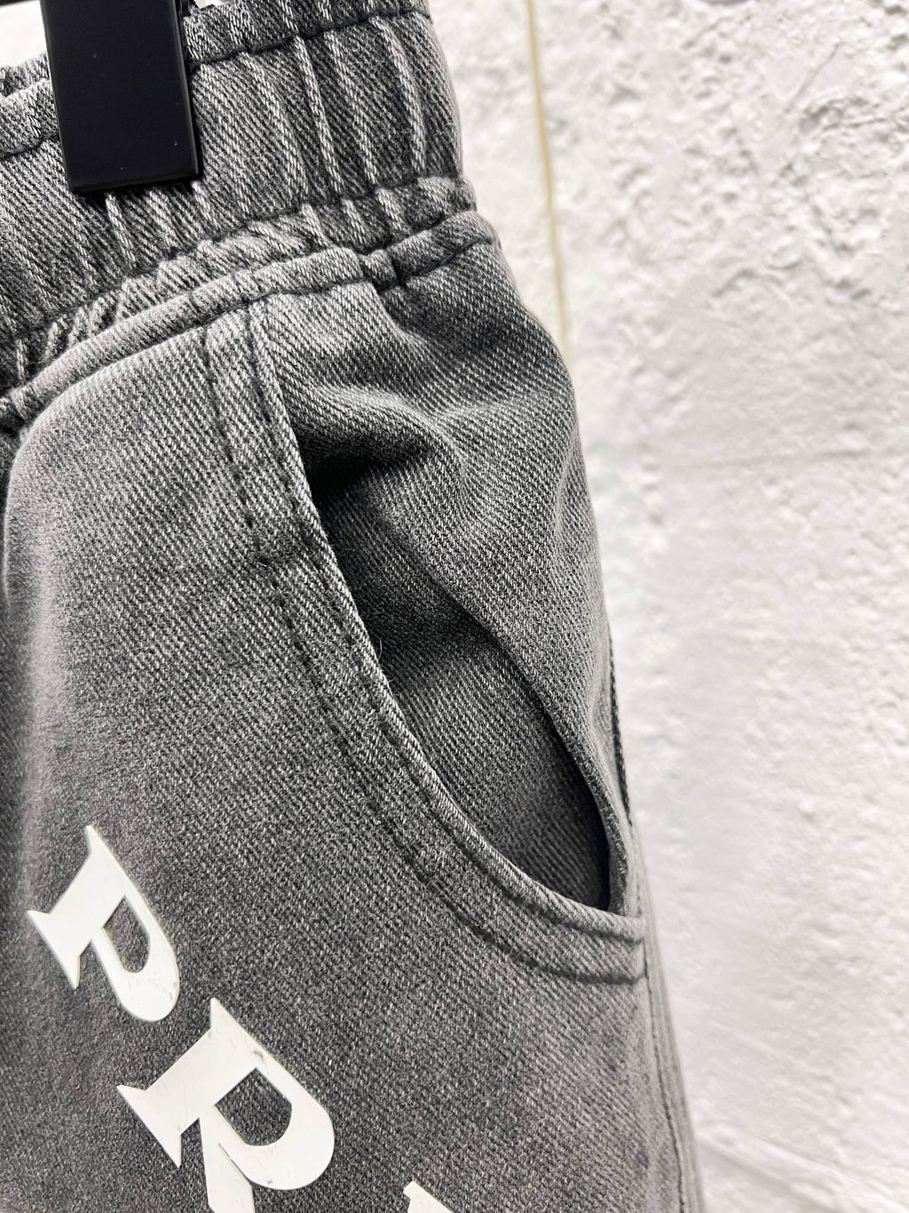 Gray denim pants waistband detail with drawstring and PRADA print
