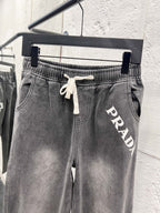 Dark gray denim pants with drawstring waist and PRADA lettering on thigh