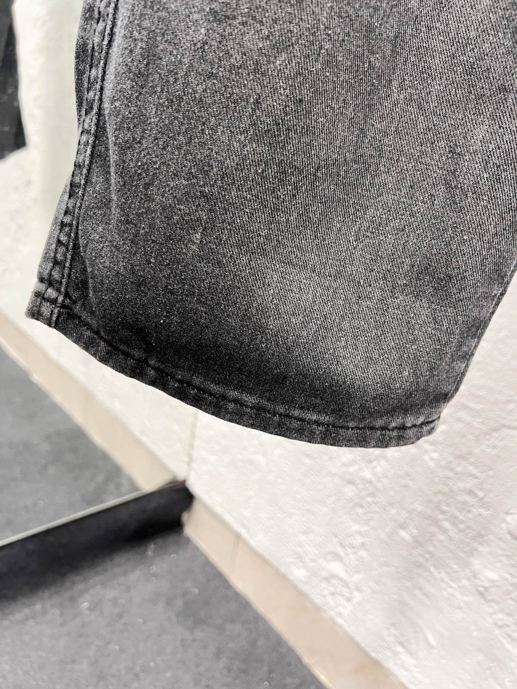Dark gray denim fabric with curved hem and stitched cuff detail