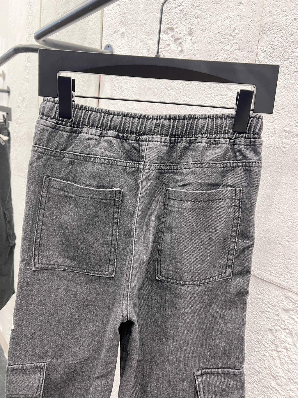 Dark gray denim pants with front pockets, stitched cargo pocket, elastic waist