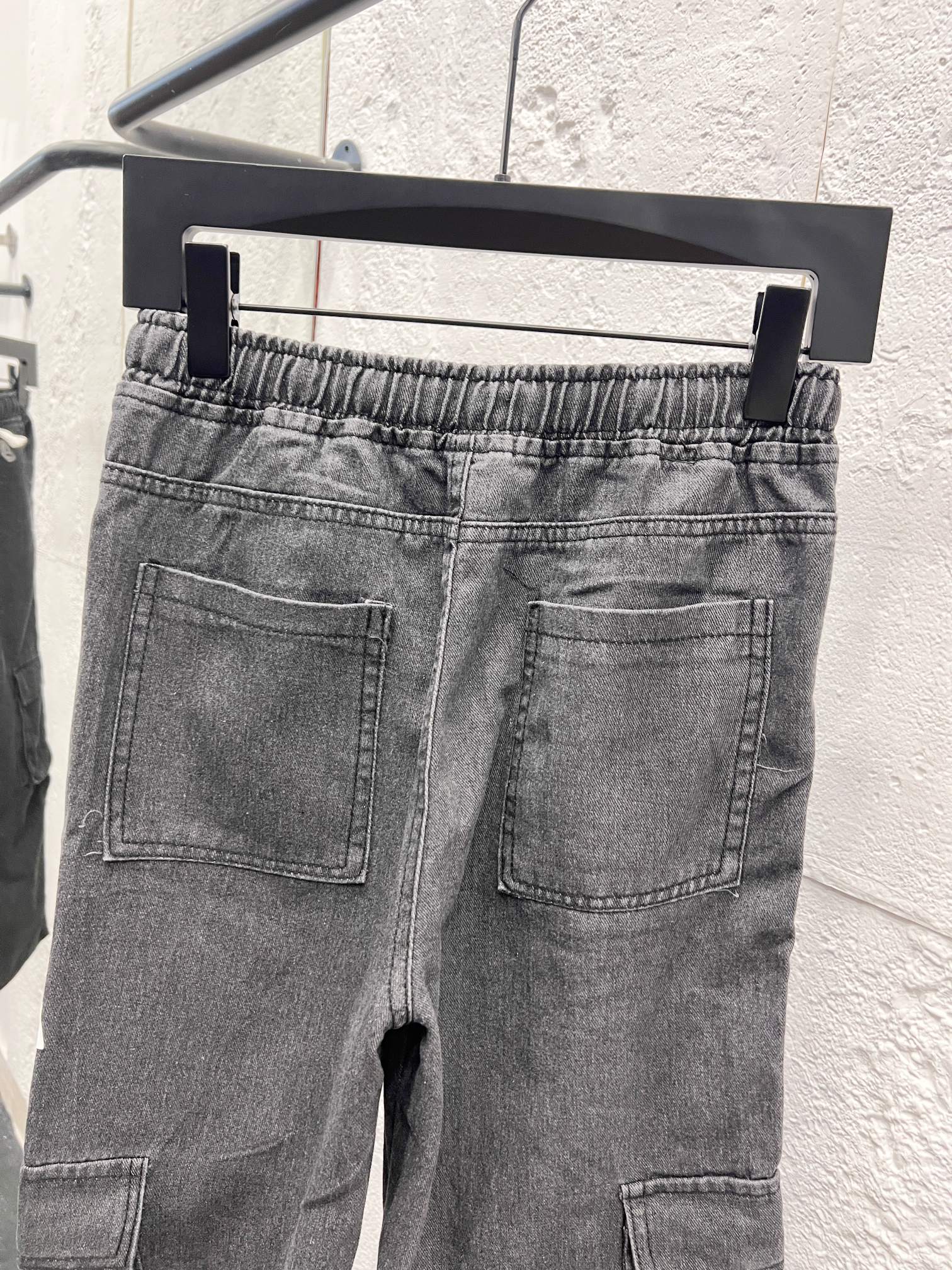Dark gray denim pants with front pockets, stitched cargo pocket, elastic waist