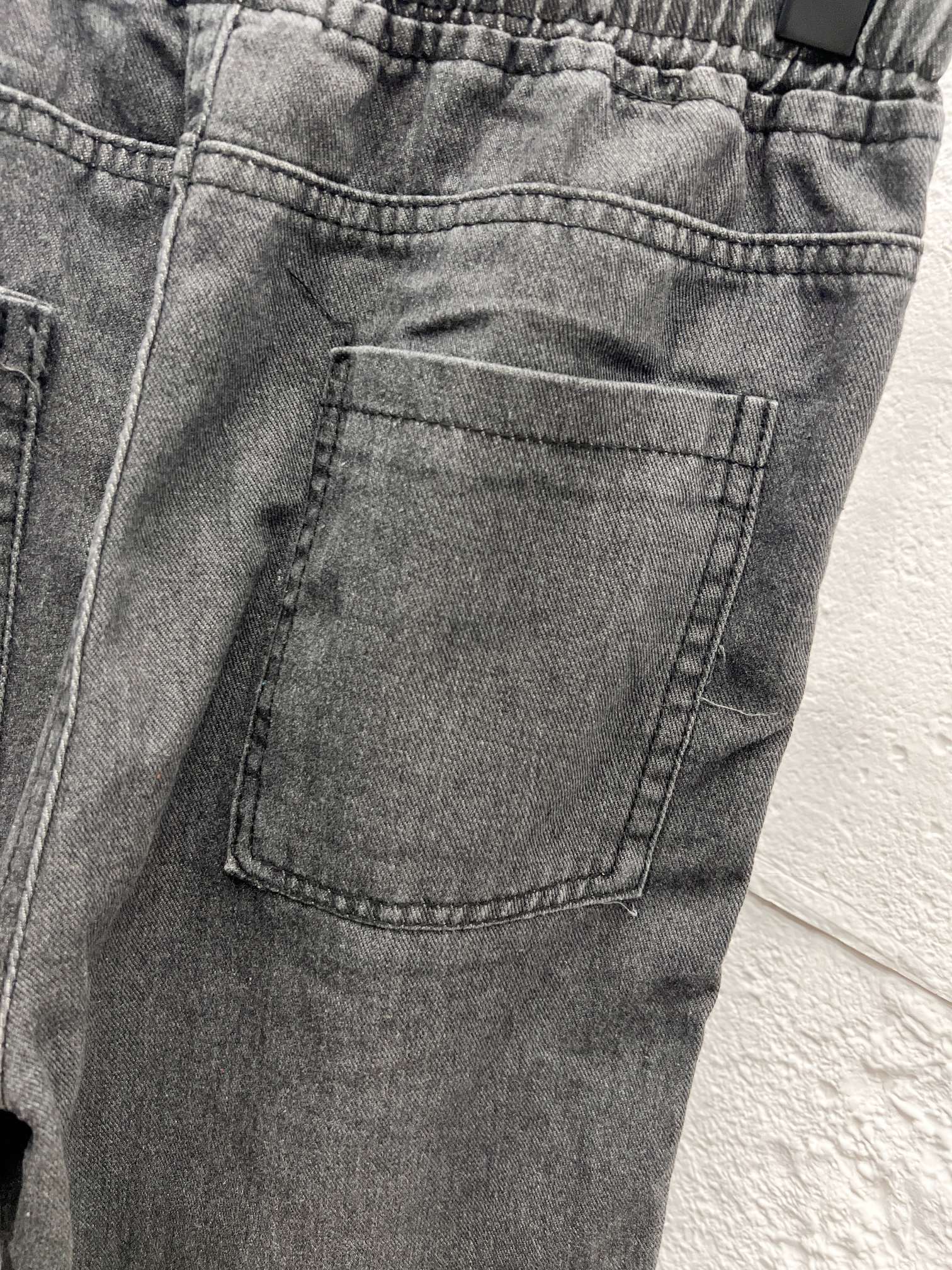 Dark gray denim cargo pocket with stitched details on front leg