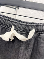Dark gray denim pants waistband with white drawstring bow detail