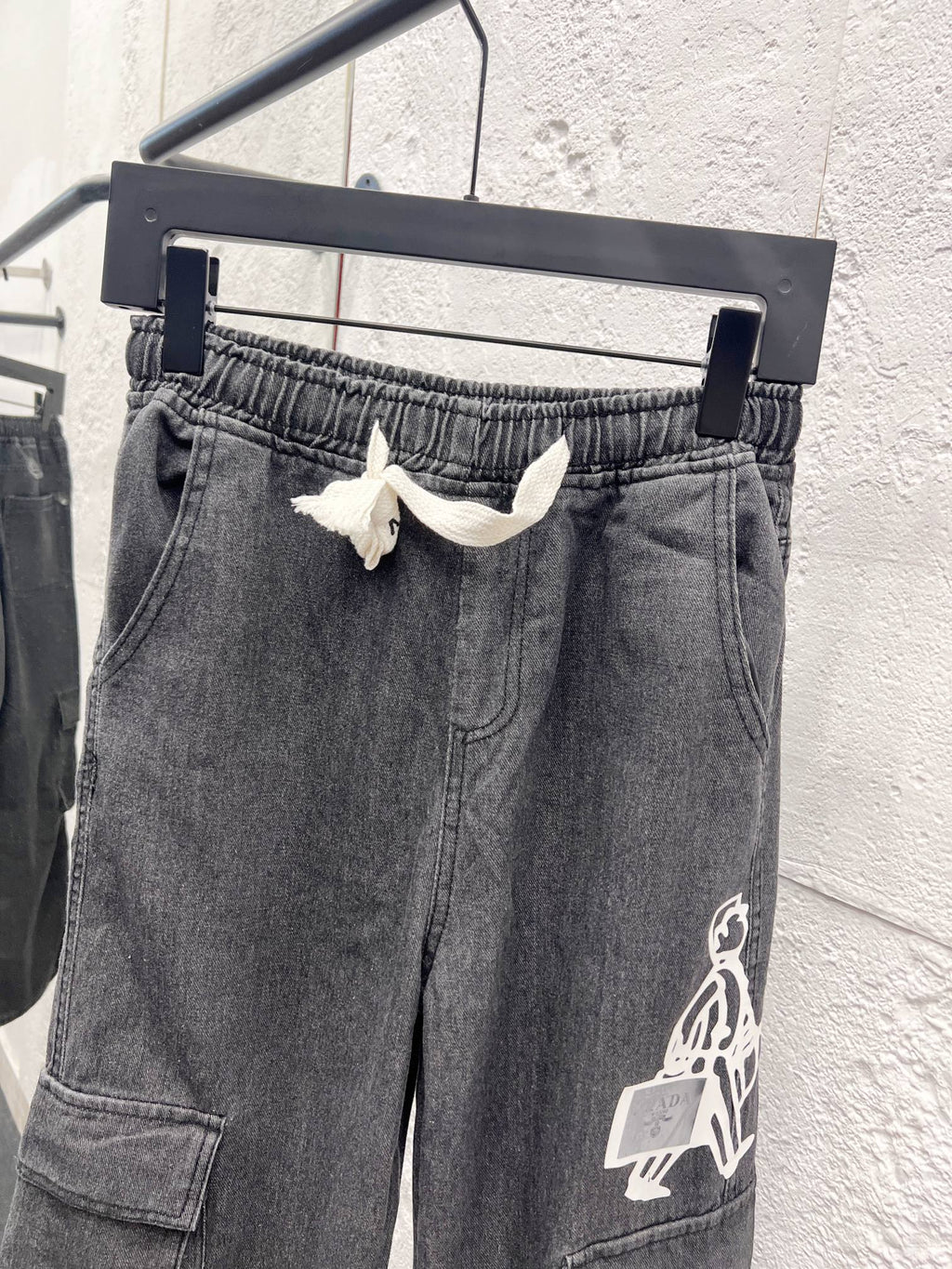 Dark gray denim pants with elastic waistband and large graphic patch