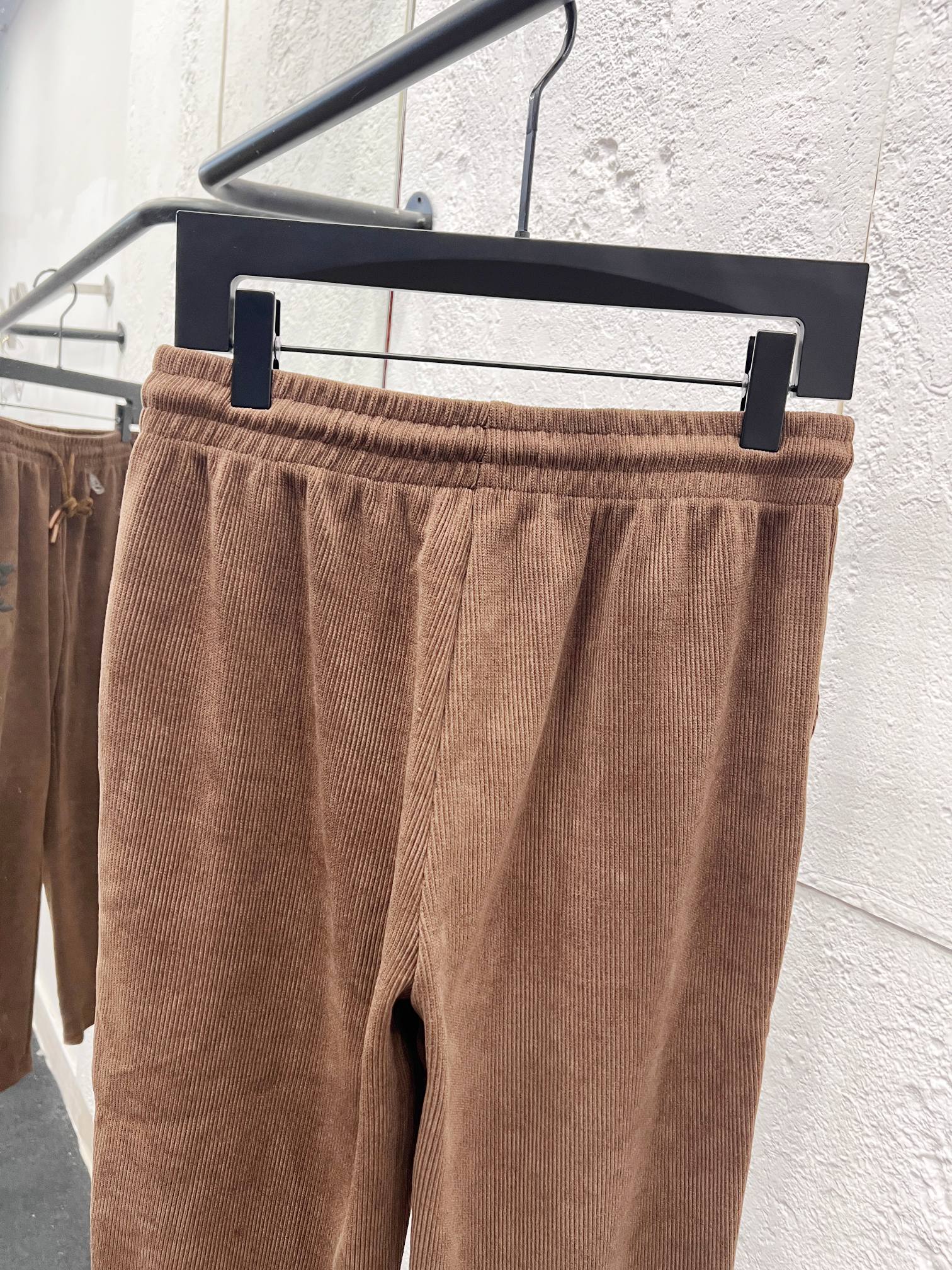 Brown corduroy pants with elastic waistband and drawstring on hanger