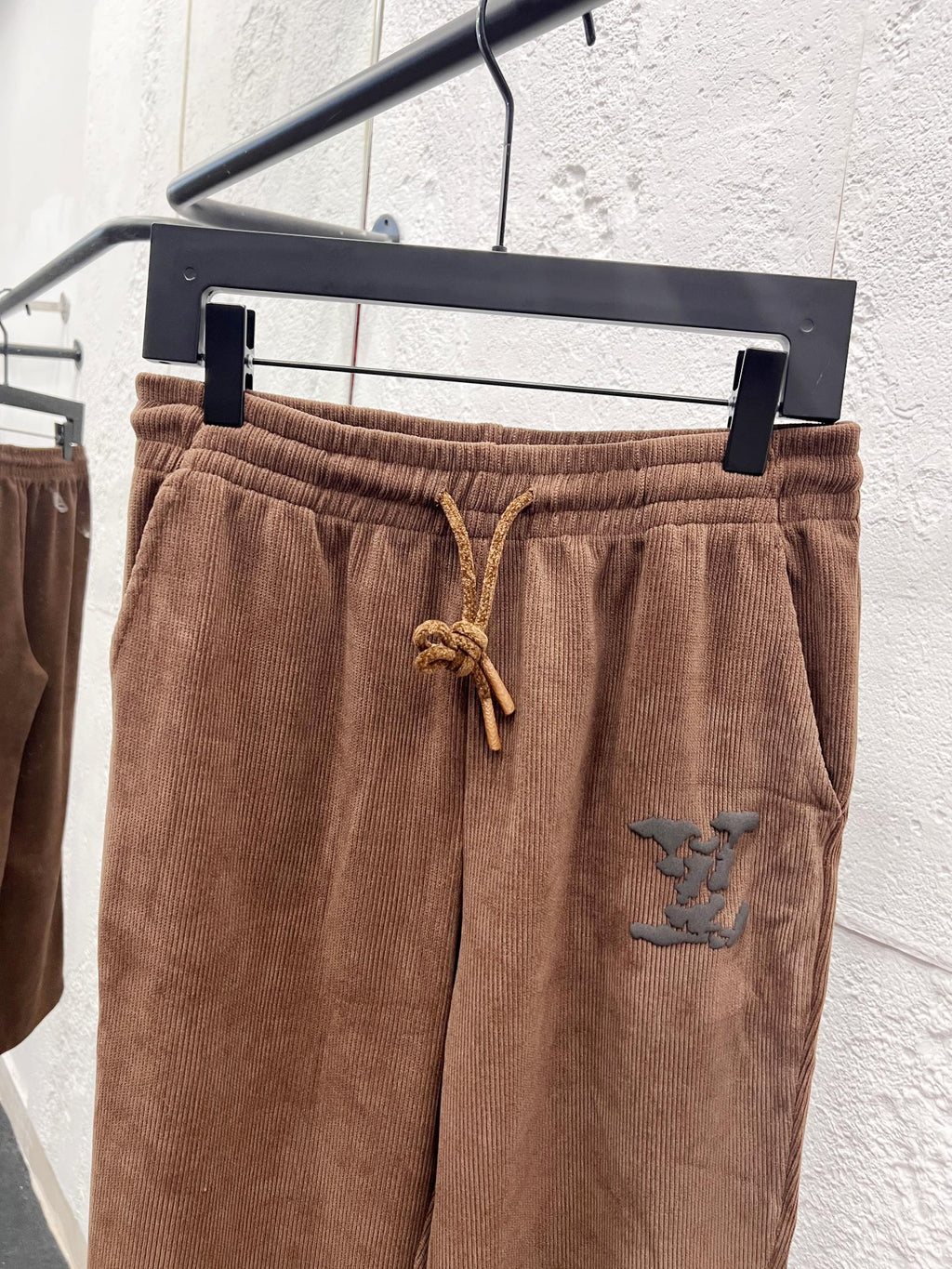 Brown corduroy pants waistband with drawstring and small embroidered logo patch