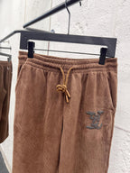 Brown corduroy pants waistband with drawstring and small embroidered logo patch
