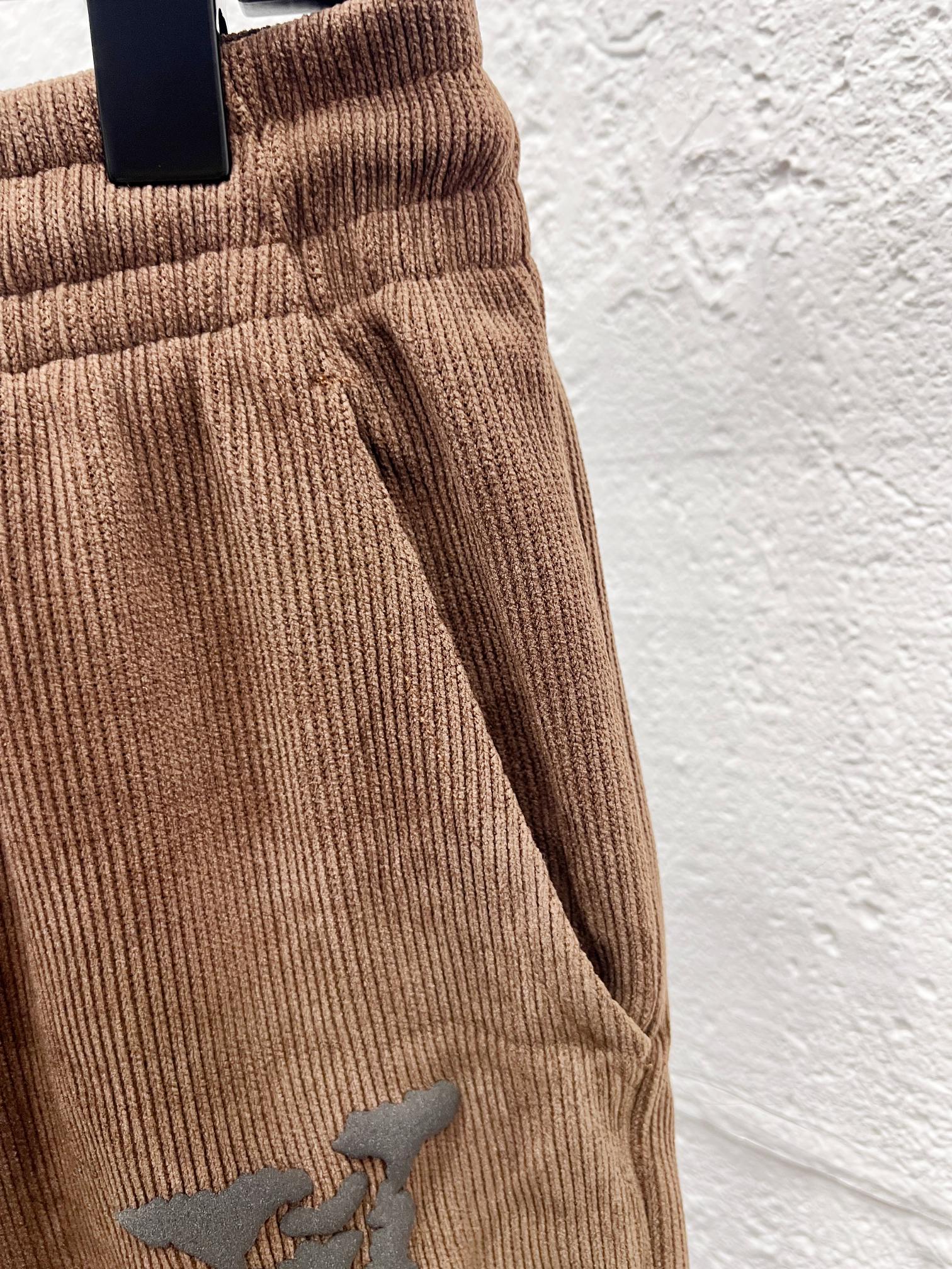 Brown corduroy pants side view with drawstring and embroidered logo detail