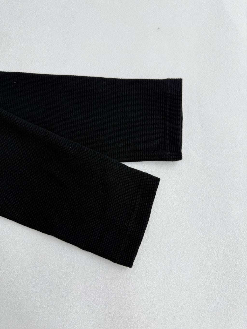 Black long-sleeve shirt sleeve with ribbed cuff and stitched hem