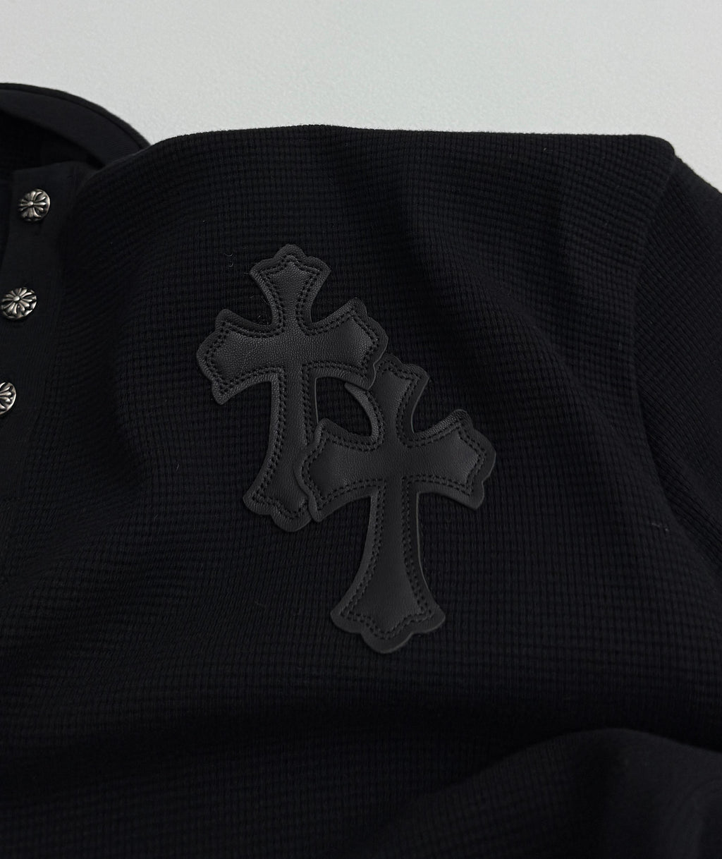 Black long-sleeve shirt with large cross appliqué on the chest