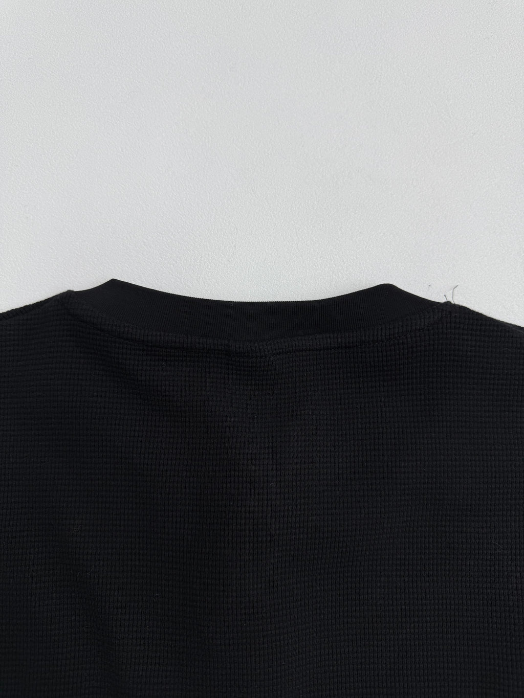 Black long-sleeve shirt back with crew neckline and textured fabric surface