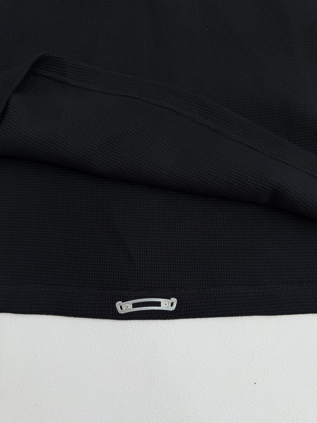 Black long-sleeve shirt cuff with snap-button detail at the hem