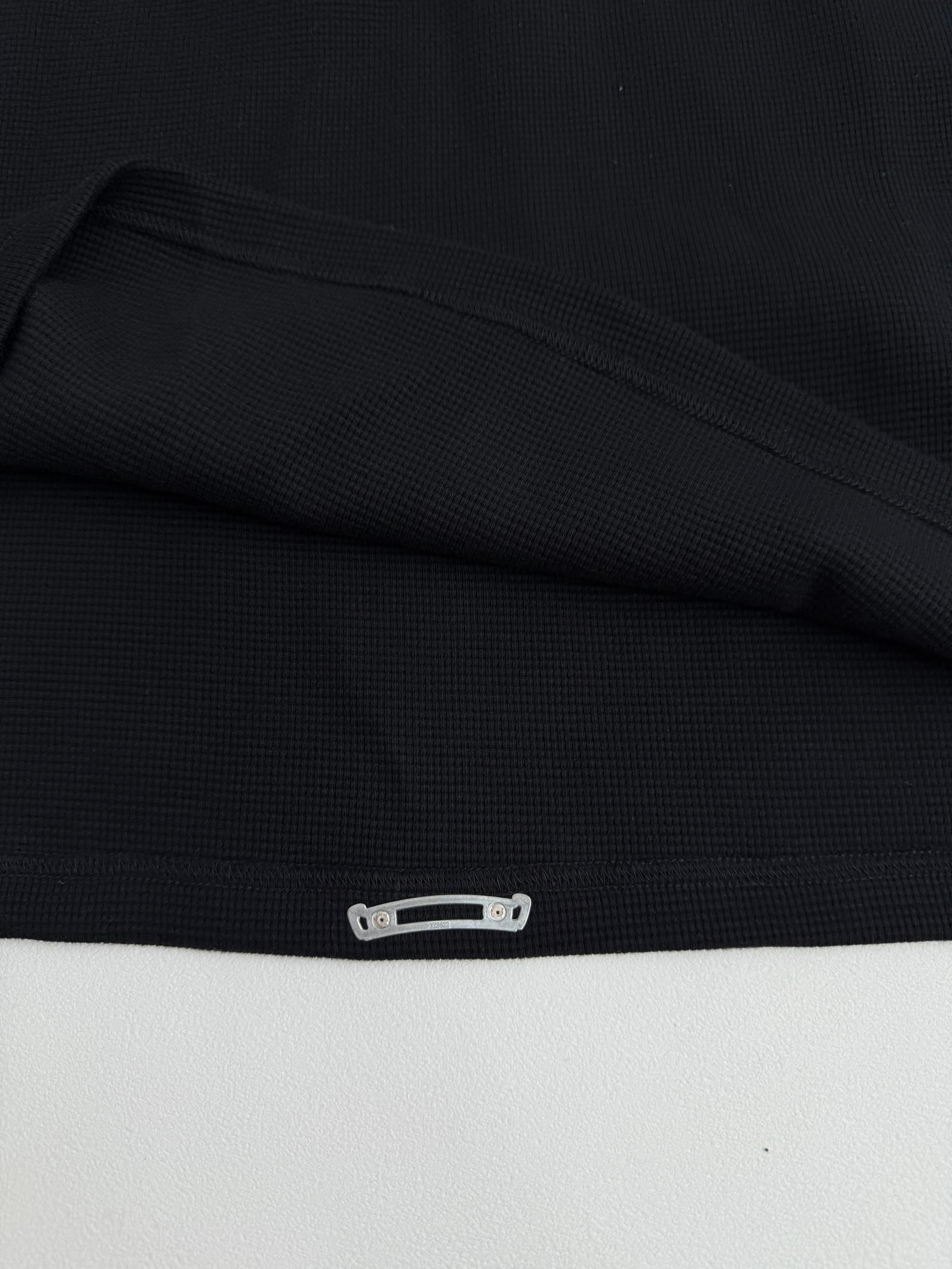 Black long-sleeve shirt cuff with snap-button detail at the hem