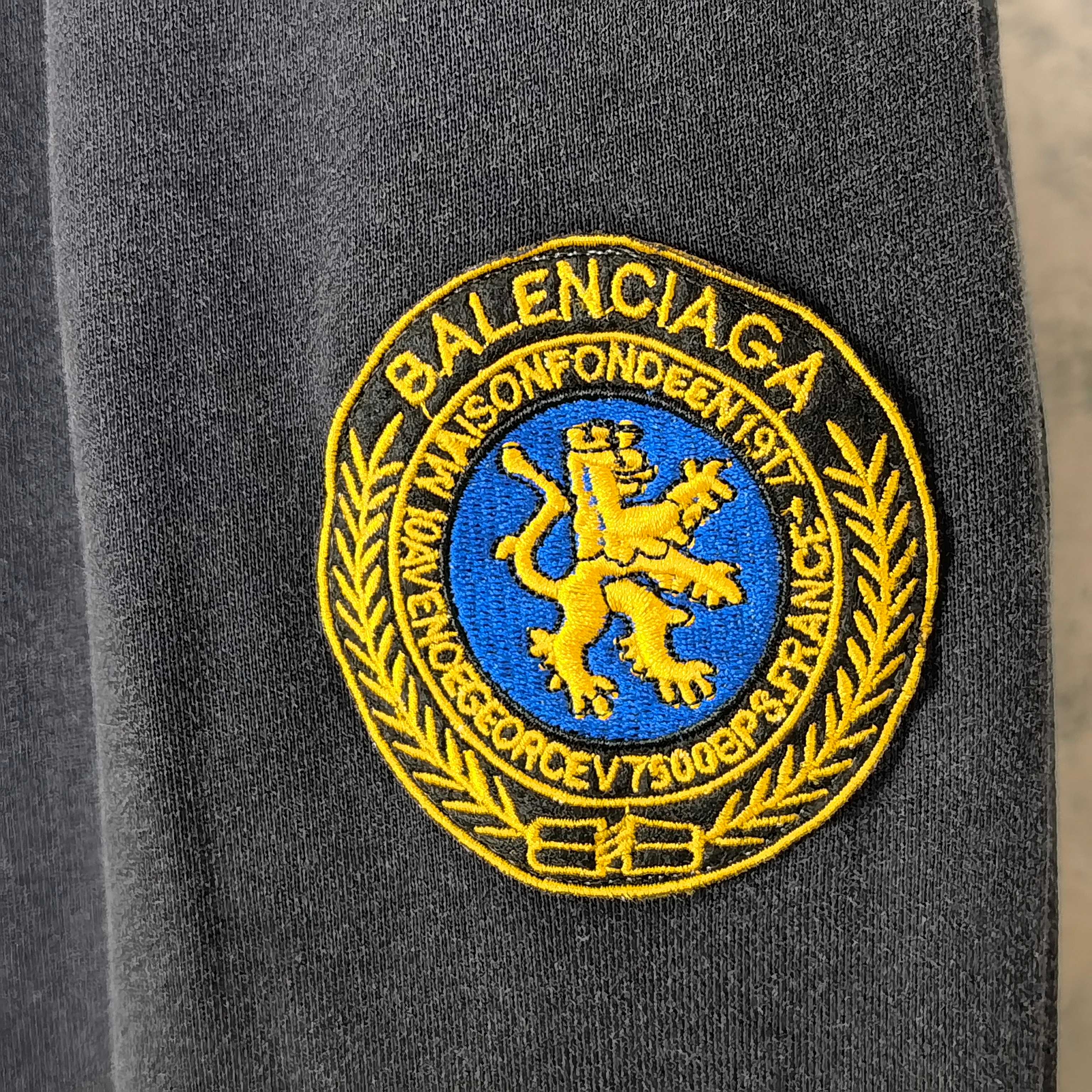 Balenciaga logo patch in yellow and blue on dark navy fabric